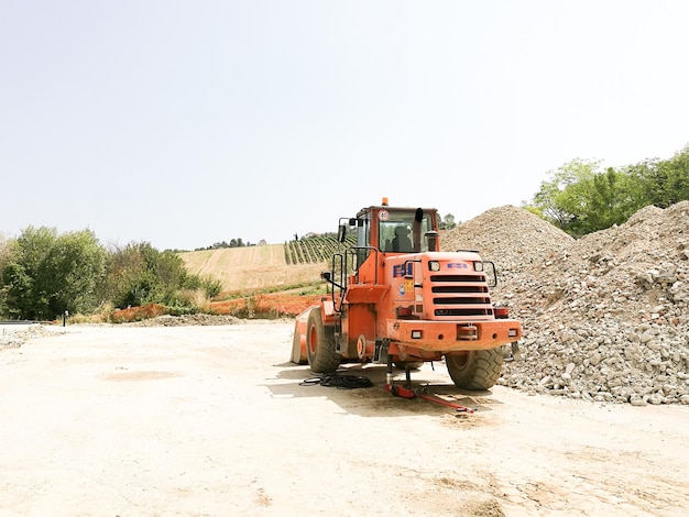 Photo tractor by heap of stones against clear sky