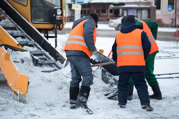 雪から道路を掃除するトラクター。掘削機は、市内の大量の雪の通りを掃除します。労働者は冬に道路から雪を一掃します。