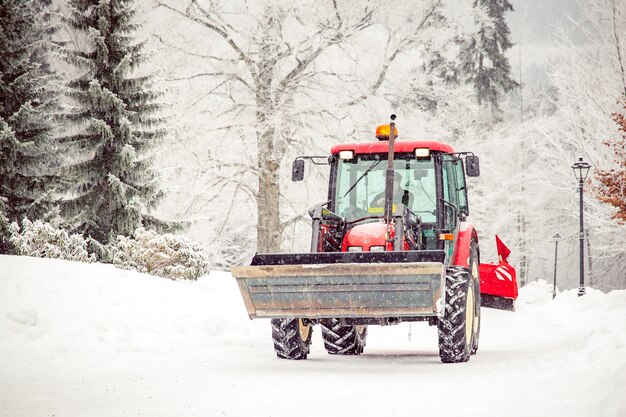 Photo tractor cleans road from snow in the winter