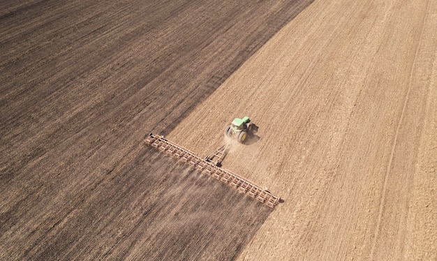 The tractor cultivates the soil. To retain moisture in early spring. Aerial view.