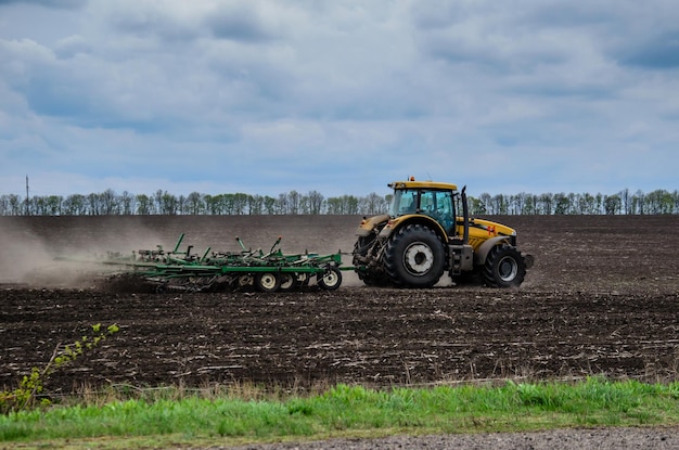 Tractor cultivating field on cloudy spring day