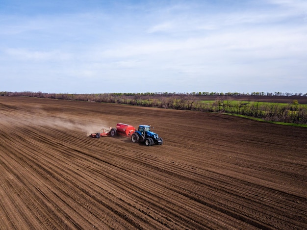 Tractor cultivating fields under blue sky Photo from drone