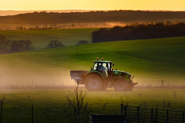 Tractor in farmland working on soil field with sunset big equipment countryside scene