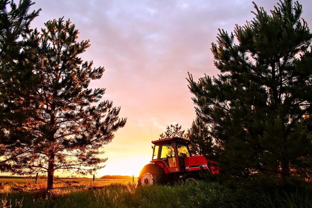 Photo tractor on field against sky during sunset