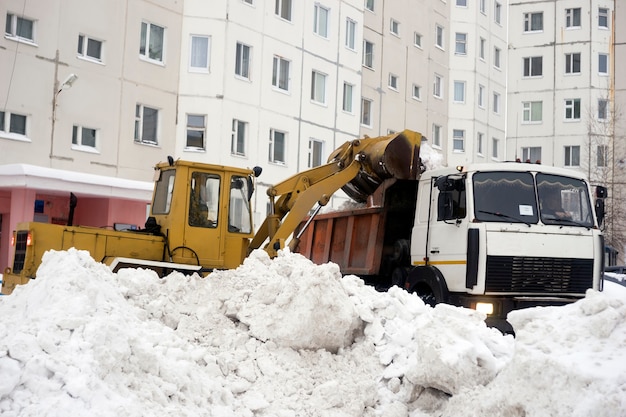 Il trattore carica la neve della carrozzeria raccolta nel cortile