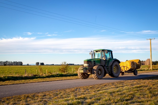 Foto tractor op de weg door landbouwveld tegen de lucht