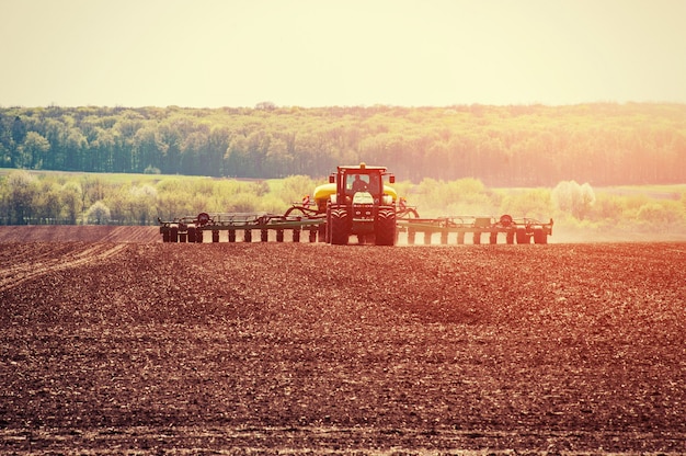 Трактор вспахивает поле фермы в рамках подготовки к весенней посадке