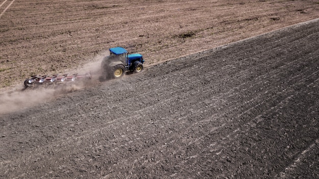 Tractor plowing field top view, aerial photography with drone