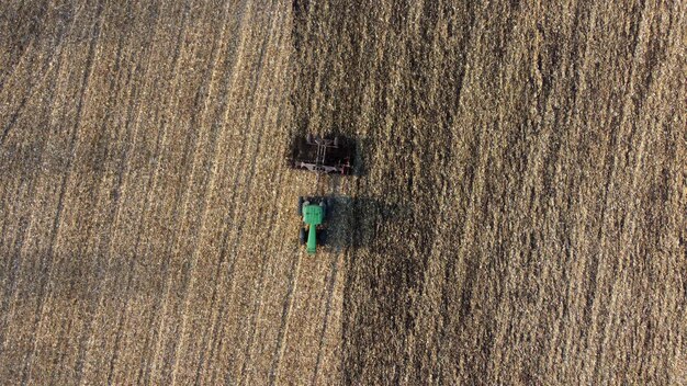 Tractor plowing ground yellow field after harvesting wheat on autumn day Aerial
