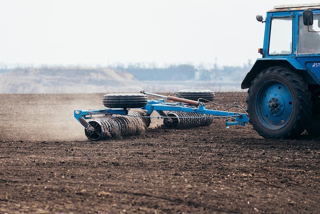 The tractor processes the field in spring harvester in work on\
sowing wheat and grain cropsxa