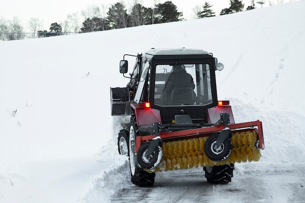 Photo tractor removes snow from the road in winter