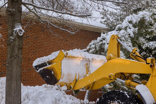 Tractor removing snow on parking lot for car after snowfall