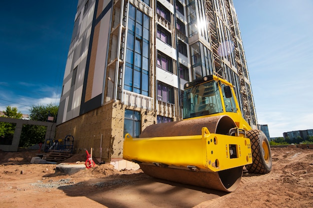 tractor roller compacts the ground at a new house under construction