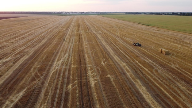 Tractor schoonmaken verzamelen stapels stro tarwe oogsten op zomeravond