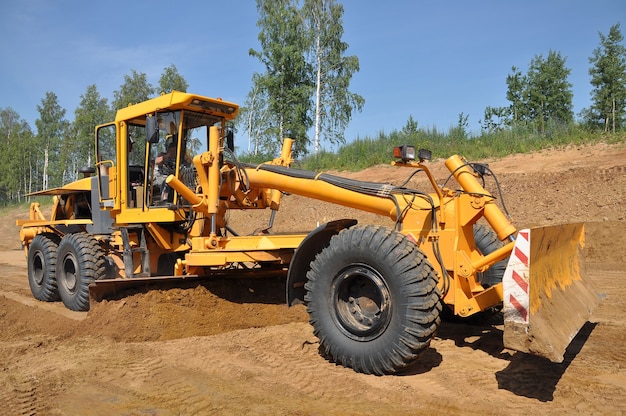 Tractor scraper levels the ground of a new road