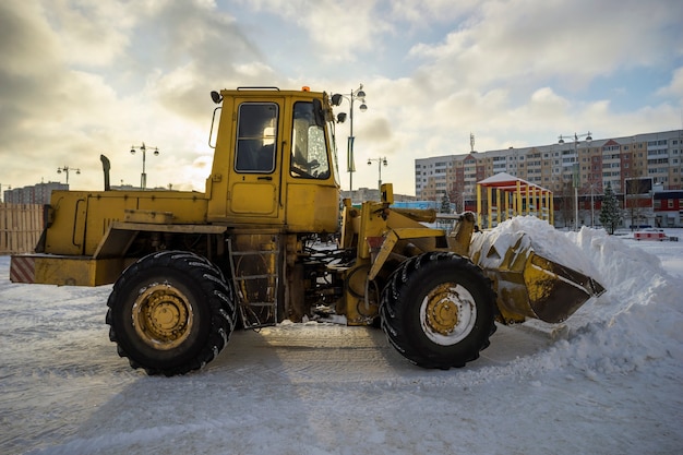 Tractor shovel snow in a pile on the street.