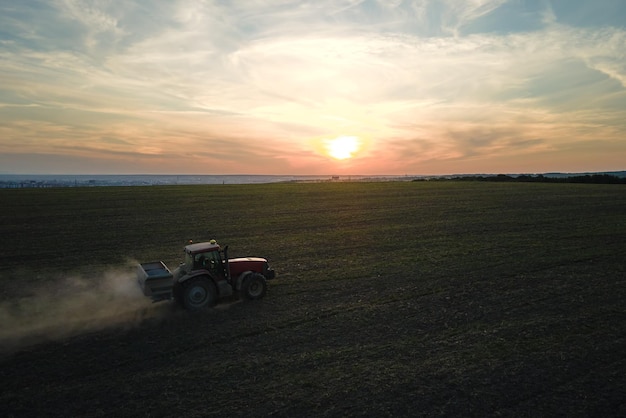 Photo tractor spraying fertilizers with insecticide herbicide chemicals on agricultural field at sunset