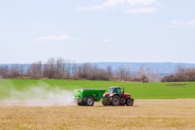 Tractor spreading fertilizer on grass field.