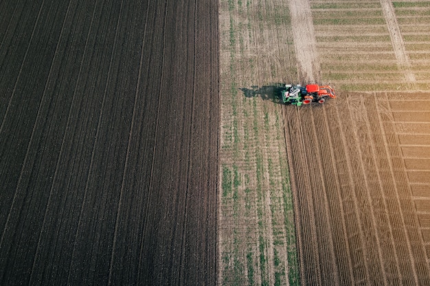 シーダー付きのトラクターは、耕作地に穀物を播種するための土地を準備します。航空写真。