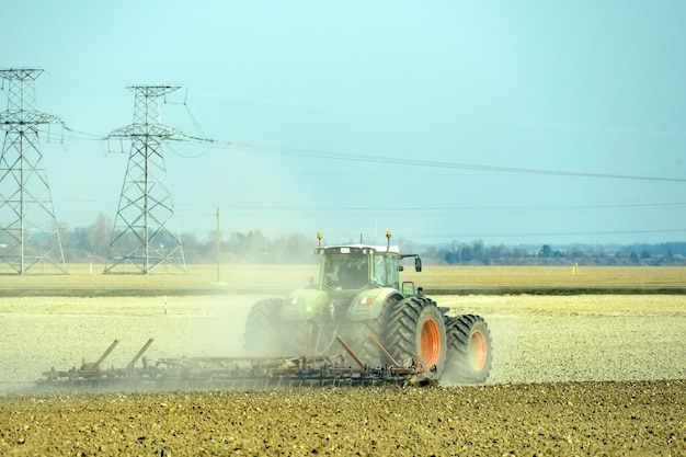 Tractor with a plow working in the field A farmer driving a new modern tractor plows the land Neatly and smoothly plowed field The beginning of the agricultural season Cultivation of cereals