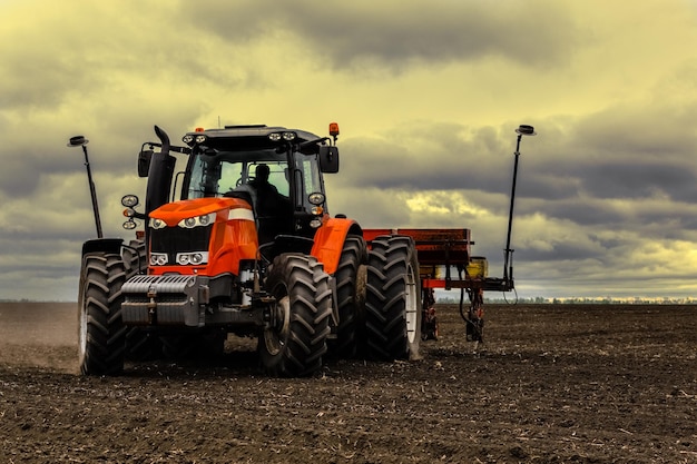 A tractor with a seed drill is engaged in planting corn Tinted photo