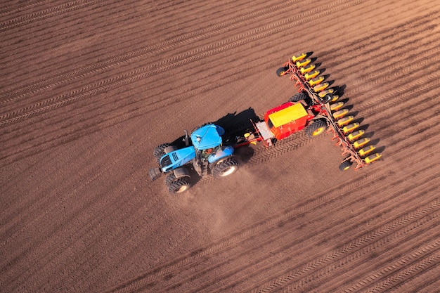 Tractor with seeder on field drone view