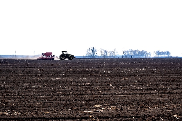 Tractor with seeder in the field in early spring