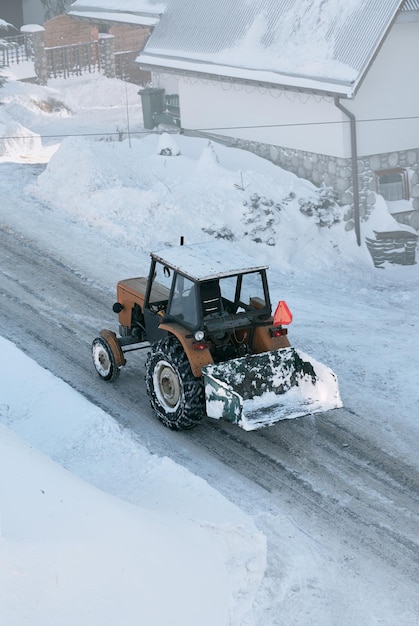 Tractor working in the winter on public roads Snow removal machine cleans snow at a city street and a parking lot after snowfall