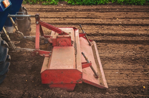 Il trattore lavora il terreno del campo allentandolo e mescolandolo ammorbidimento della distruzione del terreno