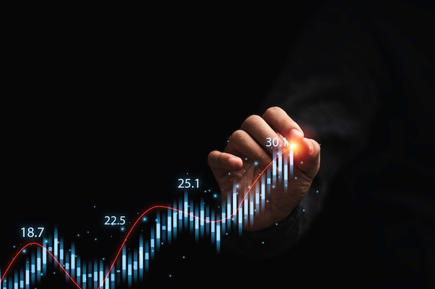 Trader drawing stock market graph chart on dark background for technical investment analysis concept.