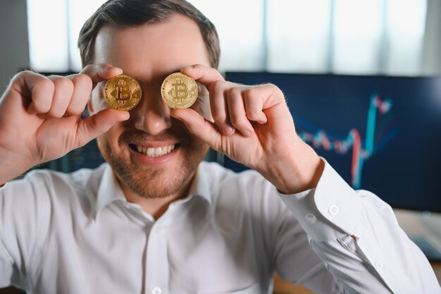 Trader holding bitcoin coins on his face