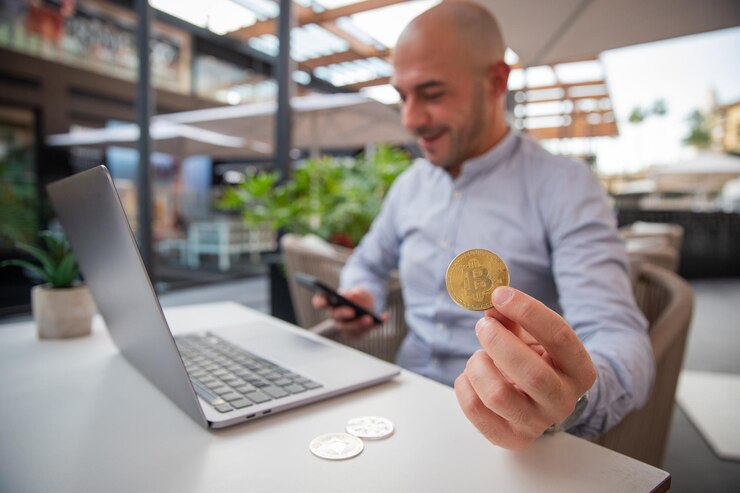 Photo trader monitors the market with his smartphone while holding a bitcoin coin