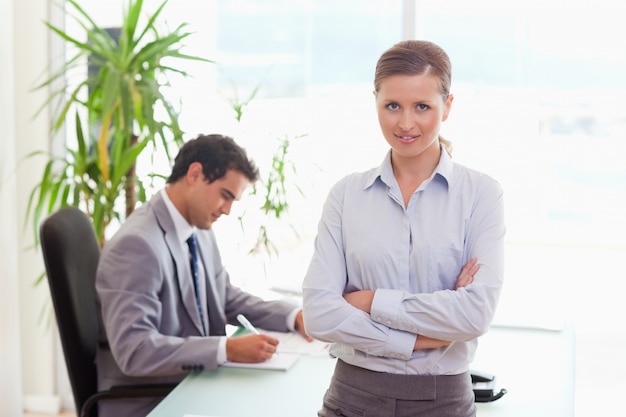 Tradeswoman with arms folded and colleague sitting behind her