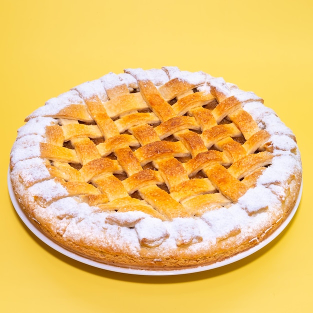 Tradition american apple pie with sugar crust on yellow background