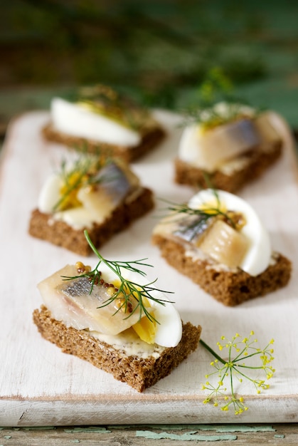 Tradition Danish open sandwich smorrebrod with herring, egg, mustard and dill. Dark bread sandwich.