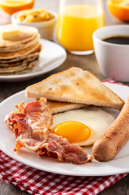 Traditional American breakfast with fried egg,toast,bacon and sausage on wooden table