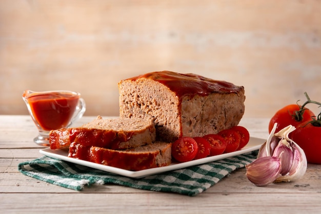 Traditional American meatloaf with ketchup on wooden table