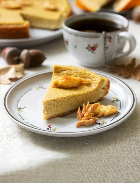 Torta fatta in casa tradizionale zucca americana, decorata con biscotti su uno sfondo di zucche e foglie di autunno.