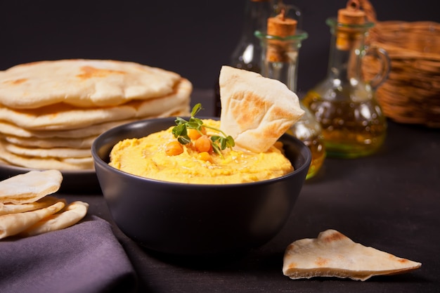 Traditional appetizer hummus with chickpea served with fresh pita bread and herbs.