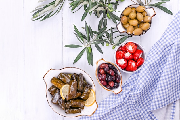 Traditional appetizers, olives from Greek cuisine. White wood background. View from above. Fresh branches of olives. Copy space