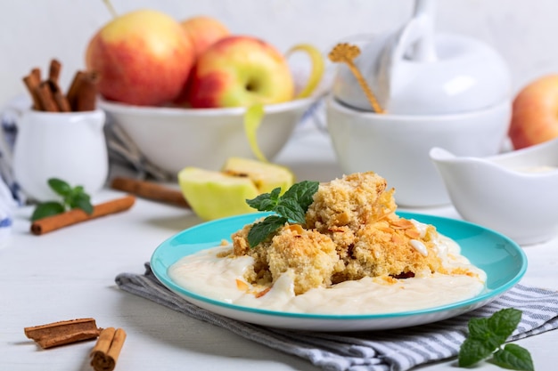 Traditional apple crumble served with custard and fresh mint sprig selective focus sweet autumn baking concept