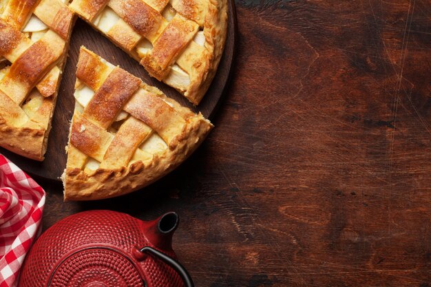 Традиционный яблочный пирог на деревянной доске и чайнике Верхний вид с копировальным пространством