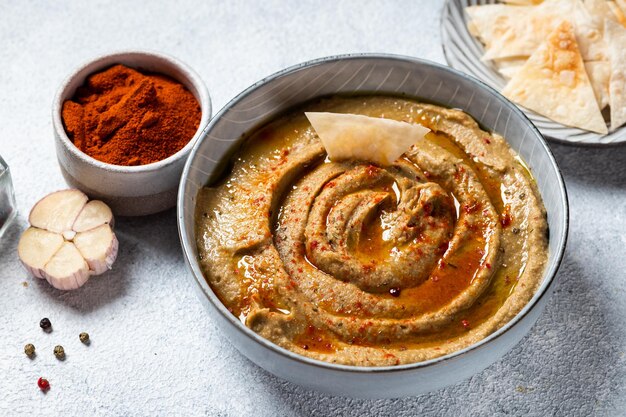 Traditional arabian eggplant dip baba ganoush with herbs and smoked paprika on light background Eggplant hummus Babaganush or eggplant caviar Baked eggplant Turkish eggplant dip