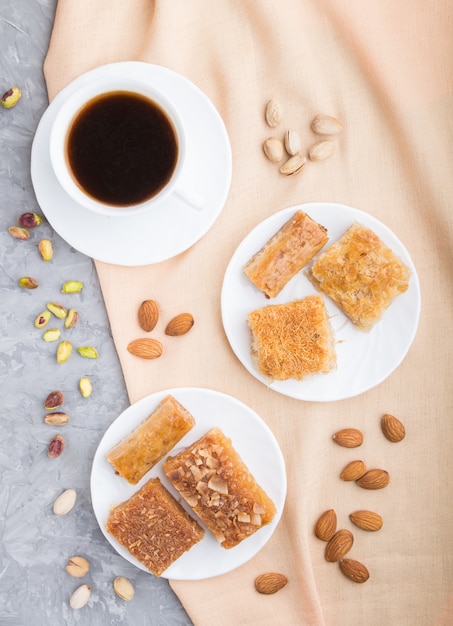 Traditional arabic sweets and a cup of coffee on a gray concrete background.  top view, close up.