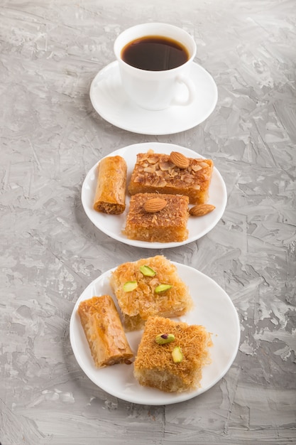 Traditional arabic sweets on white plate and a cup of coffee. side view.