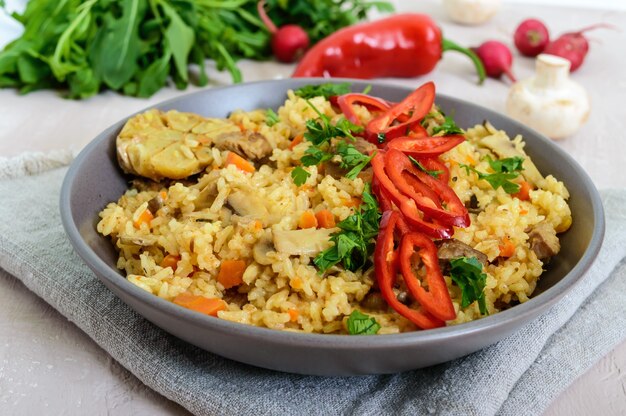 A traditional Asian dish - pilaf with meat, mushrooms and pepper capi in a bowl.