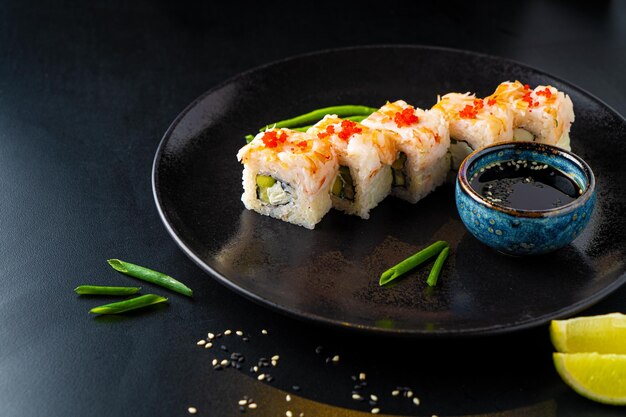 Traditional Asian rolls and sushi with soy sauce and wasabi served on a dark background