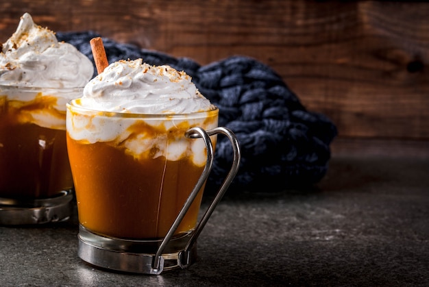 Traditional autumn dishes. Halloween, Thanksgiving. Hot and spicy aromatic pumpkin latte with cinnamon on black stone table, with blanket.  copyspace