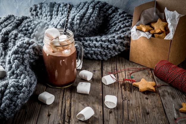 Traditional autumn winter drinks and treats. Cup of hot chocolate with marshmallow and ginger biscuit stars, in gift box, old rustic wooden table. Cozy atmosphere, copy space