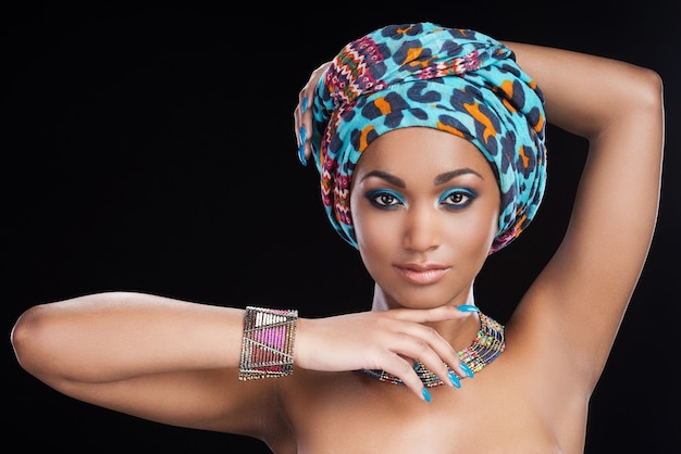 traditional beauty. beautiful african woman in headscarf and jewelry posing against black background